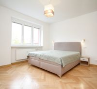 Bright bedroom with a bed and wood-patterned flooring in a two-room apartment.