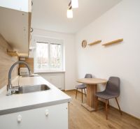 A kitchen in a 2-room apartment with a dining table, wooden decor, and a window.