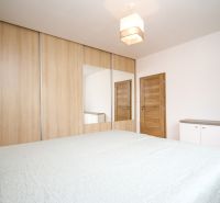 A room with a bed, a wardrobe with sliding doors and a mirror in a 2-room apartment.