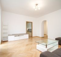 Living room of a two-room apartment with a wooden decor floor and white furniture.