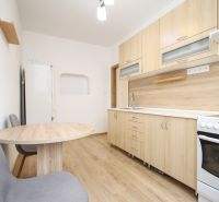 A kitchen with a wooden decor floor and wooden furniture in a 2-room apartment.