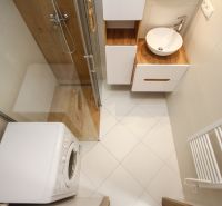 Bathroom in a 2-room apartment with a washing machine, shower, and floor with wood decor.