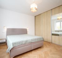 A bedroom with a bed, a wardrobe with a mirror, and a floor with a wooden decor in a 2-room apartment.