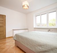 A bedroom with a bed, wooden decor flooring, and light furniture in a 2-room apartment.