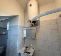Bathroom in a family house with tiled walls, a mirror, and an electric boiler.