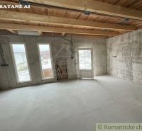 A room in a cabin with a concrete floor and a wooden ceiling, glass doors and windows.