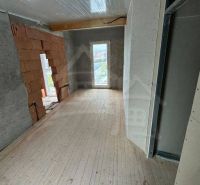 The interior of a cabin with a wooden decor floor and incomplete walls.
