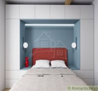 A double bed with a red headboard set between white wardrobes in the cottage.