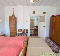 A bedroom in a family house with antique furniture and a tiled stove.