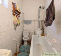 Bathroom in a family house with a bathtub, toilet, and white tiles on the walls.