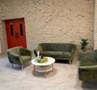Spacious office with sofas, kitchenette, and brick wall.
