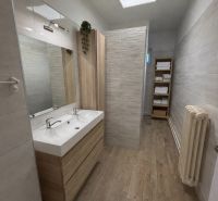 A bathroom in a family house with a double sink and a wooden decor floor.