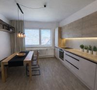 A kitchen in a family house with wooden floor decor, a dining table, and modern lighting.