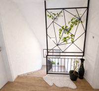 Interior of a family house with a lace rug, decorative railing, and a floor with a wooden design.