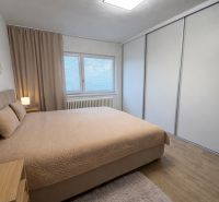 Bedroom with a bed, wardrobe, and wooden decor flooring in a family house.