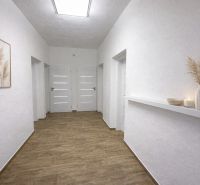Hallway in a family house with white walls, decorations, and a wooden-patterned floor.