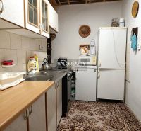 A kitchen in a cabin with carpet, equipped with appliances and wooden cabinets.