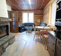 The interior of a cottage with a tiled stove, a leather sofa, and a floor with a wooden decor.
