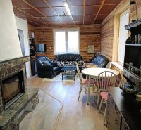 Interior of a cabin with a fireplace, leather sofas, and a wooden decor floor.