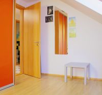 Interior of a holiday apartment with a wood-patterned floor, a television, and an orange cabinet.