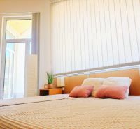 Bright interior of a holiday apartment with a comfortable bed and tall windows.