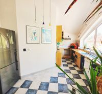 A kitchen in a holiday apartment with colorful accessories and a large window.