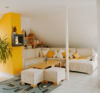 Bright living room with a corner sofa and a plant in a Holiday Apartment.