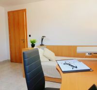 Interior of a holiday apartment with a wooden decor floor, a work desk, and cream seating.
