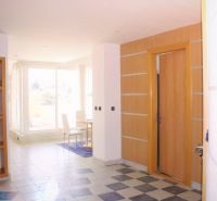 Interior of a holiday apartment with wood-patterned flooring and large windows for natural light.