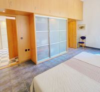 Bedroom in a vacation apartment with a sliding wardrobe and large windows.