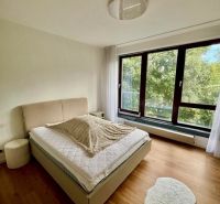 A bedroom with a light bed and a wooden decor floor in a 2-room apartment.