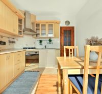 A kitchen in a 3-room apartment with a wooden decor floor and wooden furniture.