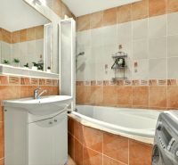A bathroom in a 3-room apartment with light tiles, a bathtub, and a sink.