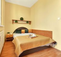 A bedroom in a 3-room apartment with a bed, a shelf, and a wooden decor floor.