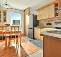 A kitchen with a wooden decor floor and a dining table in a 3-room apartment.