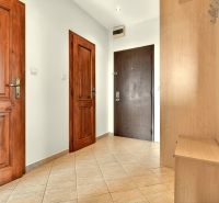 A hallway in a 3-room apartment with wooden doors and a coat rack.