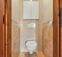 A toilet with beige tiles in a 3-room apartment.