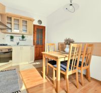 A kitchen in a 3-room apartment with wooden chairs and a floor with a wooden decor.