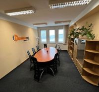 Offices with an oval table, black chairs, and wooden decor furniture.