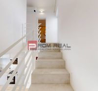 A staircase with white railing and a kitchen in a 3-room apartment.
