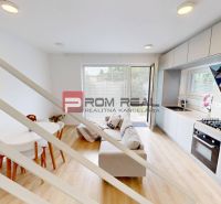 Interior of a 3-room apartment with wood-patterned flooring, kitchen unit, and sofa set.
