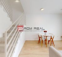 Interior of a 3-room apartment with wood-patterned flooring, stairs, and a dining table.
