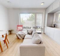 Bright kitchen in a 3-room apartment with a sofa, dining table, and large windows.