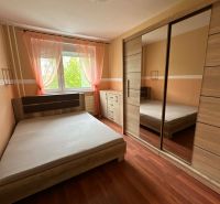 Bedroom in a studio apartment with a bed and a wardrobe, floor with wooden decor.