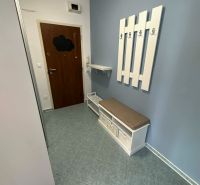 In the two-room apartment, a bright entrance with coat hooks and tiles, storage space with a seat.