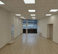 Commercial spaces with white walls, wood-patterned flooring, and large windows.