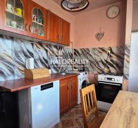 A kitchen in a 3-room apartment with wooden cabinets and appliances, flooring with a wooden decor.