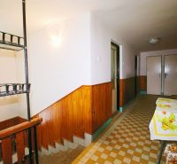 A hallway with a staircase and a table with a tablecloth in a family house.