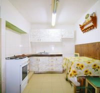 A kitchen in a family house with tiles and a table with a sunflower tablecloth.