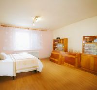 Bedroom in a family house with wood-decor flooring, bed, furniture, window.